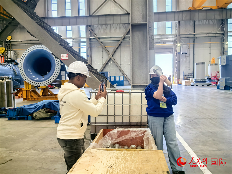 外媒記者掂量廠房內的巨型螺栓。人民網 楊春燕攝