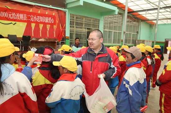 段玉平為孩子們分發愛心人士捐贈的新華字典 圖片來源：央廣網.jpg